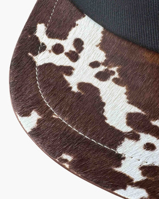 Close-up of a brown and white cowhide pattern on a 6 panel cap, with a white background.